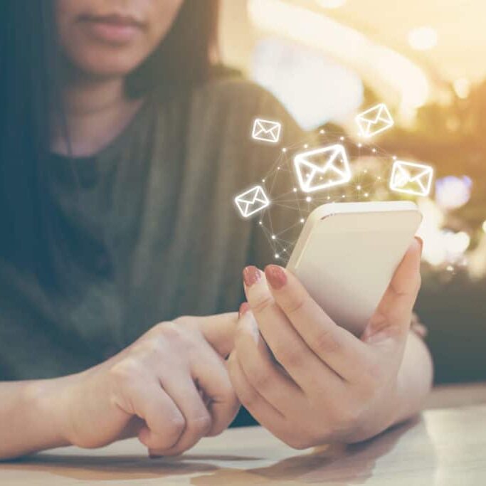 Woman uses mobile phone to get more email subscribers with small floating email symbols